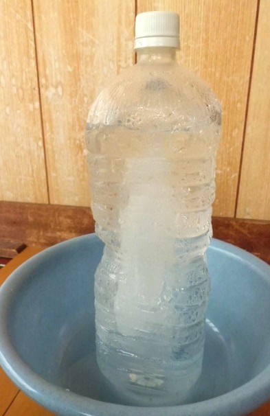 3時間後の凍った2リットルのペットボトル．外から溶け始め、氷の柱が中心に残った状態